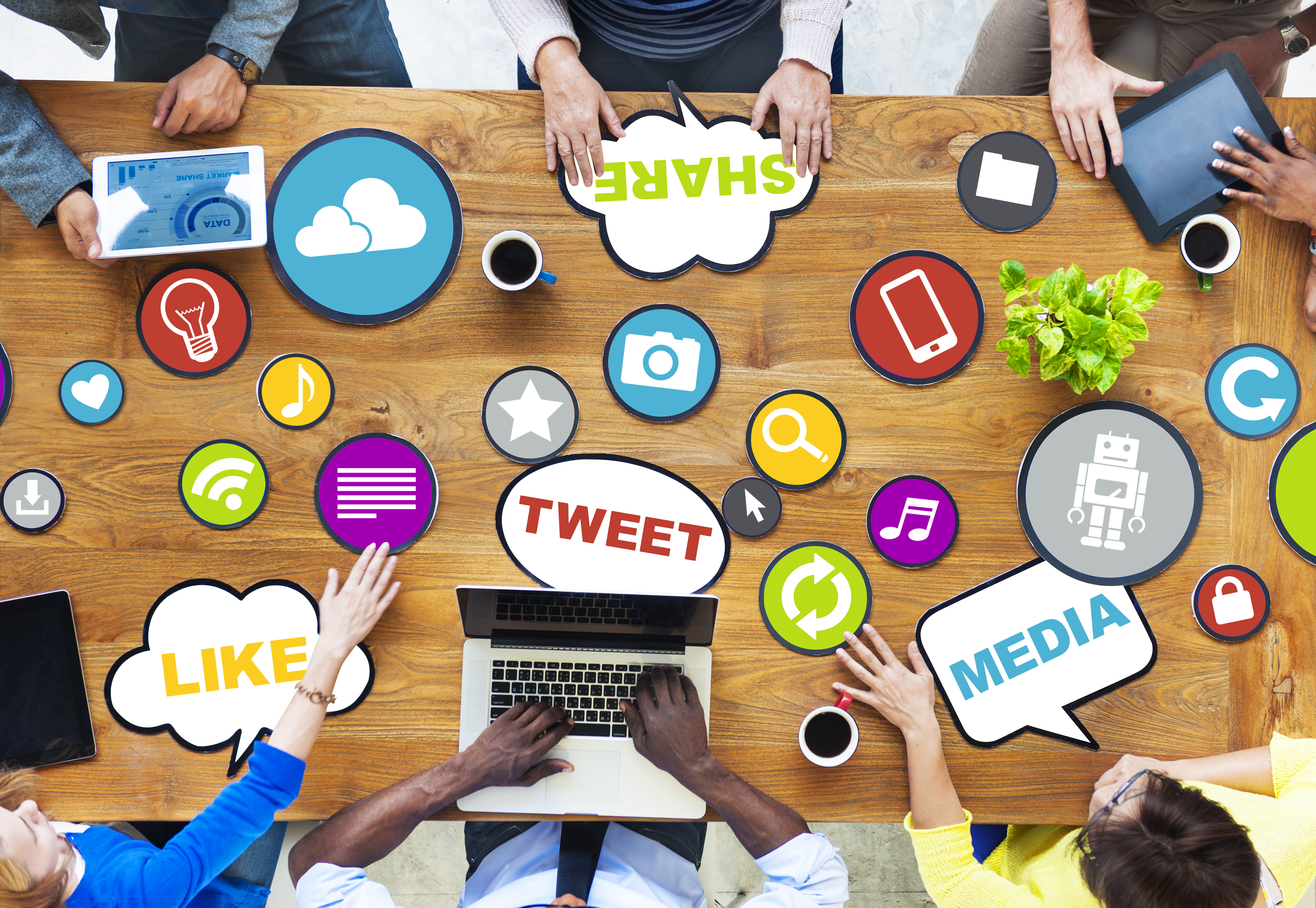 Top down view of a group of people sharing social media terms and ideas at a table through various graphics and technology